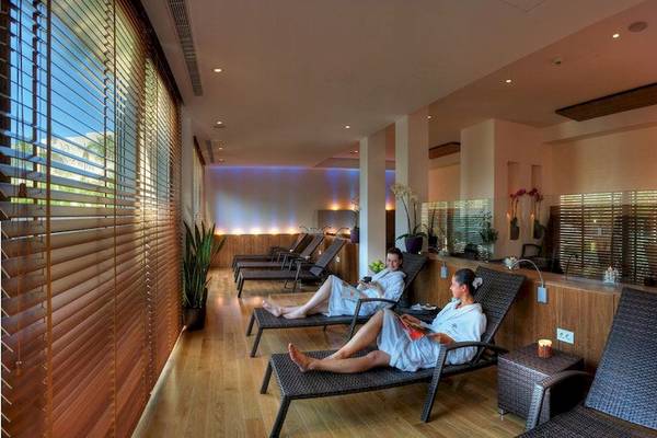 Zwei Frauen in weißen Bademänteln entspannen in der Lounge der Elite Suites by Rhodes Bay.