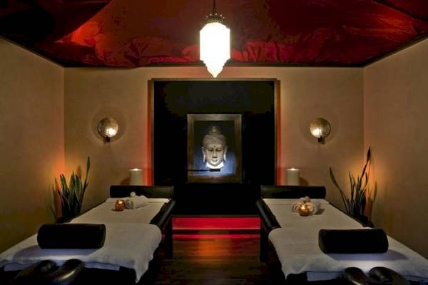 Massageraum im Elite Suites by Rhodes Bay mit zwei Massagetischen, Buddha-Bild und roten Akzentbeleuchtung.