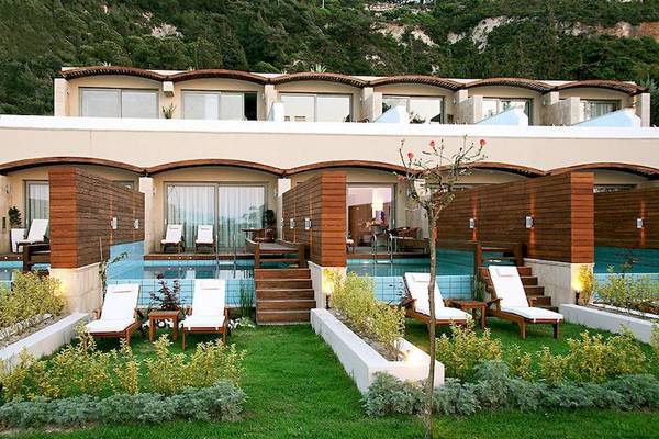 Außenbereich des Elite Suites by Rhodes Bay Hotels mit Swimmingpool und Liegestühlen.