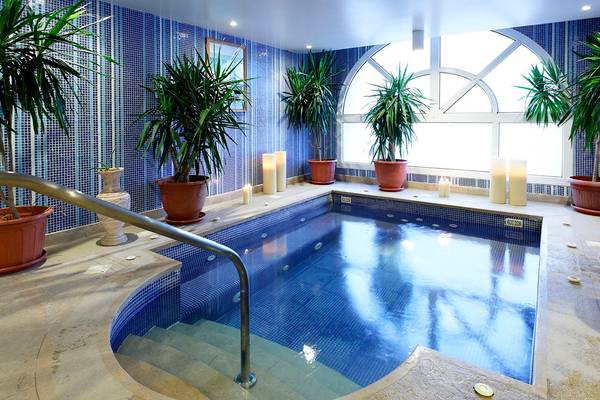 Ein kleiner, blau gefliester Poolraum im Drei Ecken Ocean View Hotel mit Pflanzen und Kerzen.