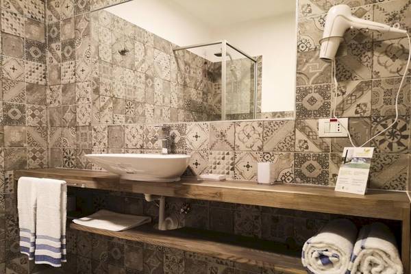 Badezimmer im Sobrado Hotel mit braunen Fliesen und einem Holzwaschtisch.