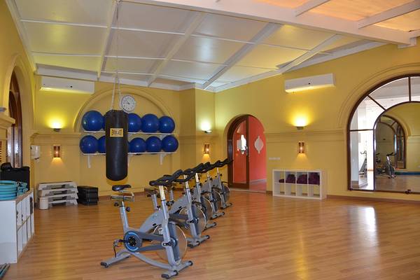 Fitnessstudio im Three Corners Ocean View Hotel mit Trainingsgeräten und blauen Medizinbällen.