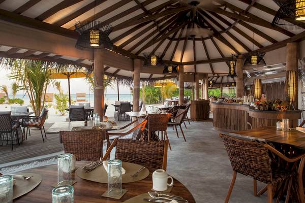 Innenansicht des Restaurants im Drift Thelu Veliga Retreat Hotel mit Tischen, Stühlen und Blick auf das Meer.