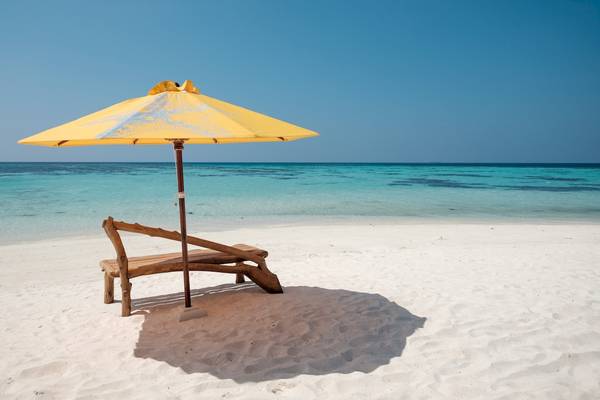 Eine Strandliege mit einem gelben Schirm im Drift Thelu Veliga Retreat