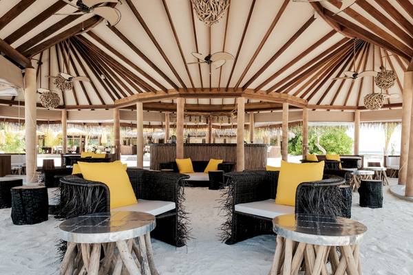 Strandlounge im Drift Thelu Veliga Retreat mit runden Sofas und Tischen auf weißem Sand.