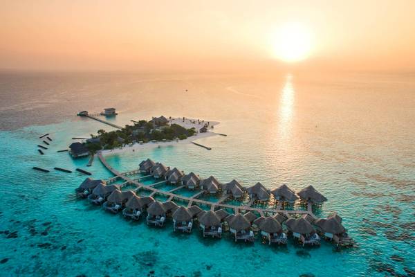 Luftaufnahme des Drift Thelu Veliga Retreats mit Wasserbungalows und Steg am Sonnenuntergang