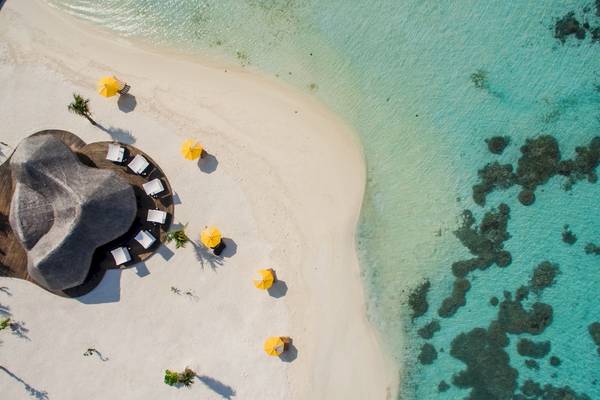 Luftaufnahme des Drift Thelu Veliga Retreat mit Strand, gelben Sonnenschirmen und Gebäuden