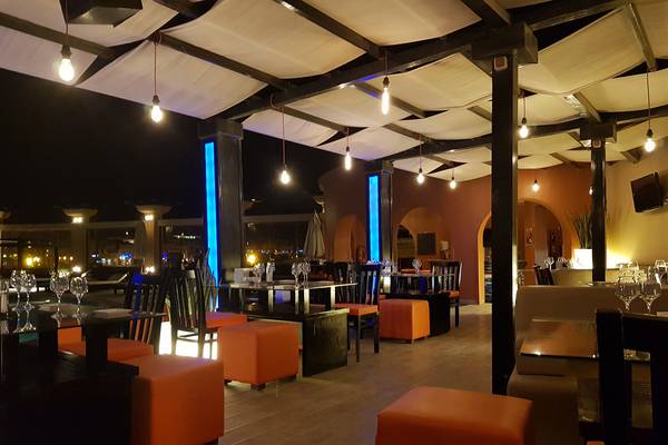 Innenansicht des Abendrestaurants im Three Corners Ocean View Hotel mit orangen Hockern und blau beleuchteten Säulen.