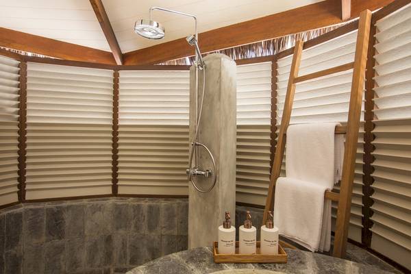 Ein Badezimmer mit einer Duschkabine und einem Holzständer mit Handtüchern im Drift Thelu Veliga Retreat.
