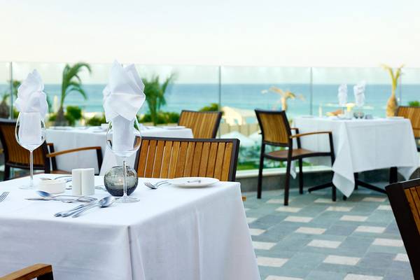 Ein Essbereich im Sunrise Pearl Hotel & Spa mit Blick auf das Meer und ein paar Tisch mit weißem Tischtuch.