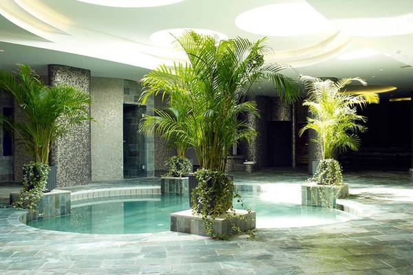 Innenpool im Sunrise Pearl Hotel & Spa mit Pflanzen und runden Deckenleuchten.
