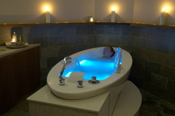 Eine Frau entspannt sich in einer beleuchteten Badewanne im Sunrise Pearl Hotel & Spa.