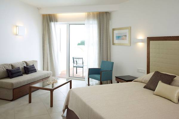 Ein modernes Hotelzimmer mit einem Sofa, einem Bett, einem Tisch und einer Terrasse.
