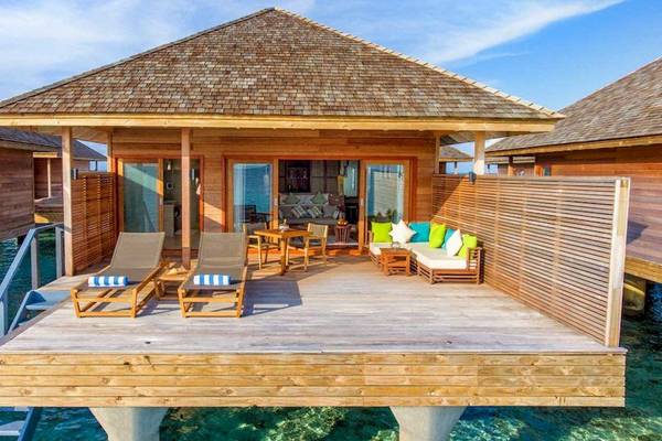 Wasserbungalow des Hurawalhi Island Resorts mit Terrasse, Möbeln und Blick auf das Meer.