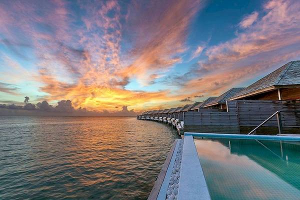 Sonnenuntergang am Hurawalhi Island Resort mit Blick auf das Meer und Wasservillen.