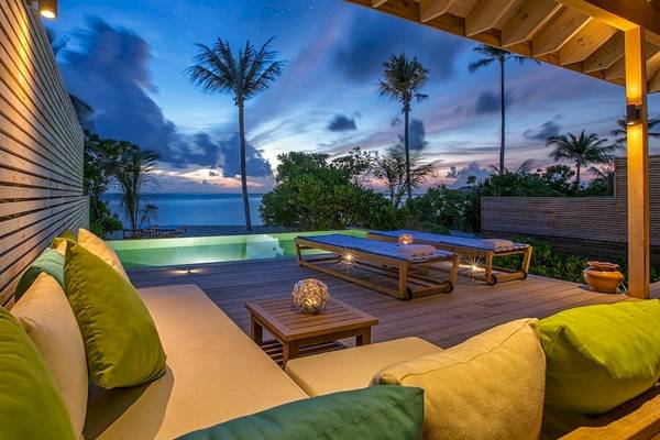 Außenbereich des Hurawalhi Island Resorts bei Nacht mit Blick auf den Ozean und zwei Loungeliegen.