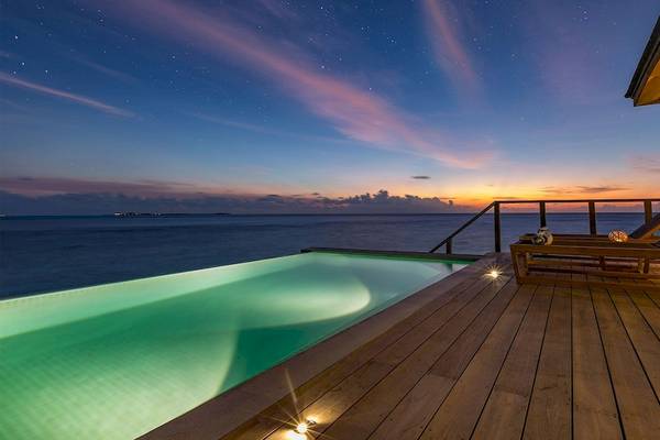 Nachtansicht des Schwimmbeckens des Hurawalhi Island Resorts mit Blick auf den Ozean und dem Sternenhimmel