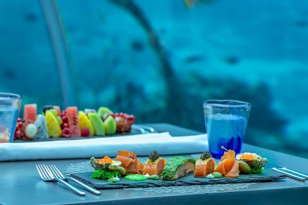 Essen auf einem Tisch im Hurawalhi Island Resort mit Blick auf ein Aquarium.