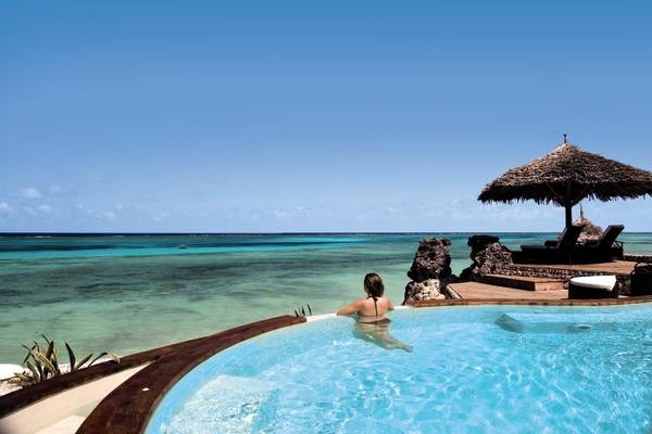Frau in einem Pool mit Blick auf das Meer und eine Hütte im Karafuu Beach Resort.