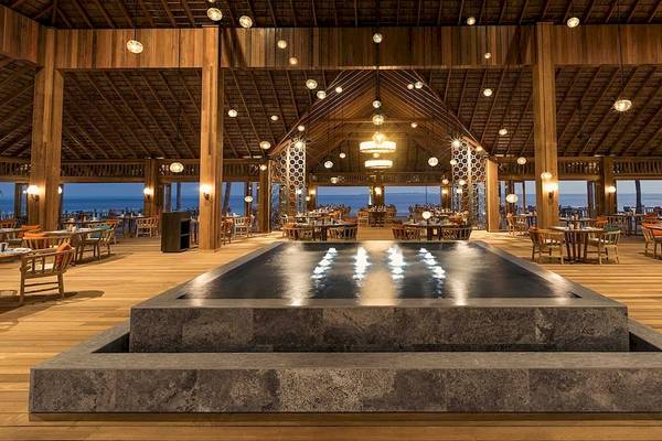 Innenbereich des Restaurants im Hurawalhi Island Resort mit Wasserbrunnen und Blick auf das Meer.