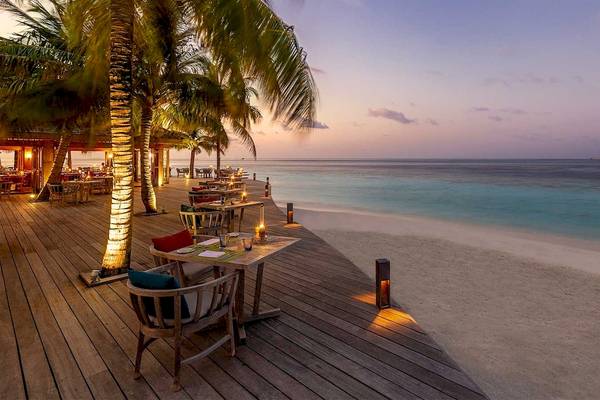 Abendessen am Strand im Hurawalhi Island Resort mit abendlicher Beleuchtung und Blick auf das Meer.