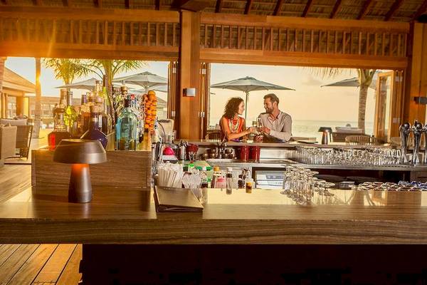 Barszene im Hurawalhi Island Resort mit Blick auf das Meer und zwei Gäste, die Getränke genießen.
