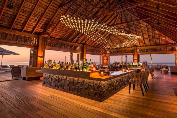 Lounge Bar des Hurawalhi Island Resorts mit Blick auf den Strand und viele Flaschen auf der Bar.