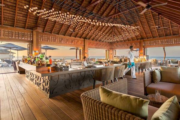 Innenbereich des Hurawalhi Island Resorts mit Bar, Tischen und Stühlen.