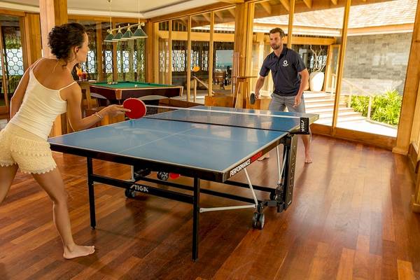 Eine Frau und ein Mann spielen Tischtennis im Hurawalhi Island Resort.