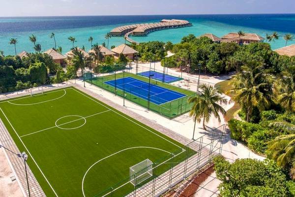Luftaufnahme des Hurawalhi Island Resorts mit Tennis- und Fußballplätzen und Blick auf das Meer.