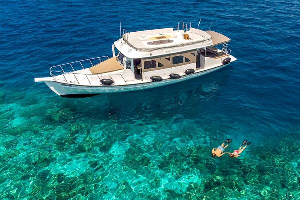 Boot im Meer am Hurawalhi Island Resort mit zwei Personen, die schwimmen.