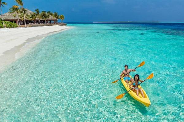 Ein Paar paddelt im Kanu am Strand des Hurawalhi Island Resorts.