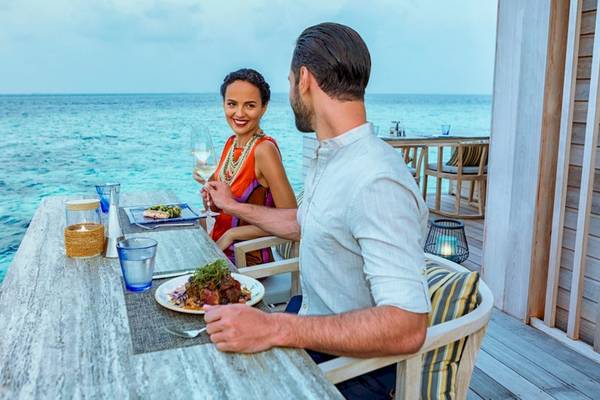 Ein Paar sitzt am Tisch mit Blick auf das Meer im Hurawalhi Island Resort.
