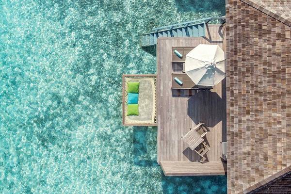 Luftaufnahme einer Wasservilla im Hurawalhi Island Resort mit überdachter Terrasse und Blick auf das Meer.