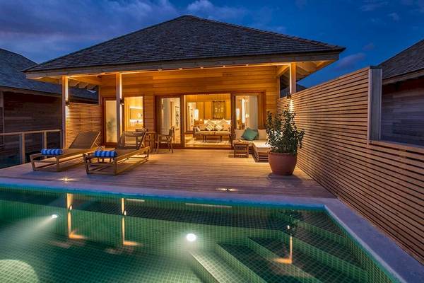 Nachtansicht der Hurawalhi Island Resort Villa mit Swimmingpool, Lounge-Bereich und illuminiertem Innenraum.