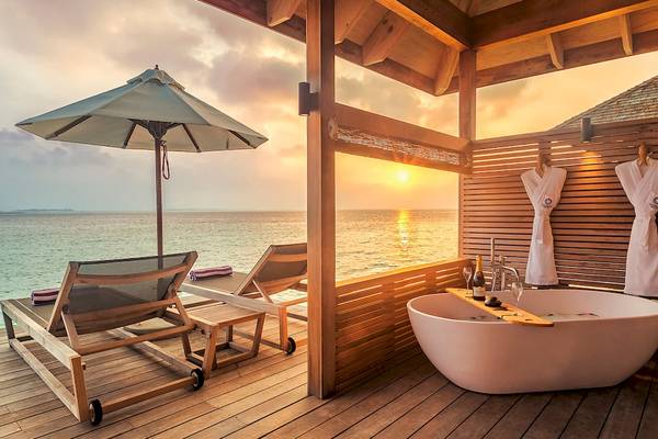 Terrasse des Hurawalhi Island Resorts mit Badewanne, Liegen und einem Schirm am Meer