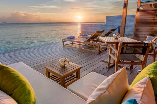 Sonnenuntergang am Hurawalhi Island Resort mit Blick auf das Meer, Loungemöbeln und Sonnenliegen.