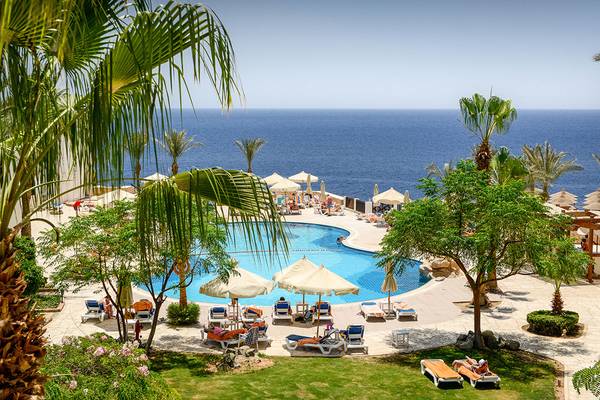 Ausblick auf das Meer vom Poolbereich des Sharm Plaza Hotels mit Liegestühlen und Sonnenschirmen.