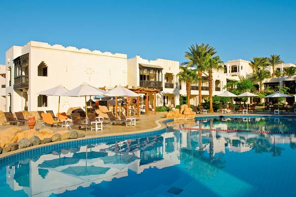 Außenbereich des Sharm Plaza Hotels mit Swimmingpool, Liegestühlen und Sonnenschirmen.