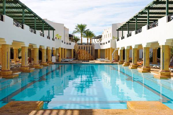 Ein großer Swimmingpool des Sharm Plaza Hotels, umgeben von Säulen und Liegestühlen.