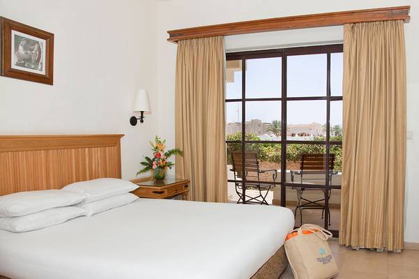 Schlafzimmer mit Bett, Tisch und Balkon im Sharm Plaza Hotel