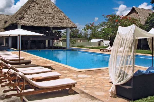 Poolbereich des Karafuu Beach Resort mit Liegestühlen und Sonnenschirmen.