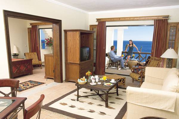 Wohnzimmer des Sharm Plaza Hotels mit Blick auf das Meer und zwei Personen, die draußen sitzen.