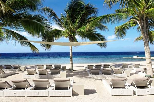 Strandszene mit Loungesesseln und Palmen am Papagayo Beach Hotel & Resort Curaçao.