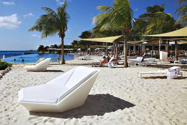 Strand des Papagayo Beach Hotel & Resort Curaçao mit weißen Liegen und Palmen
