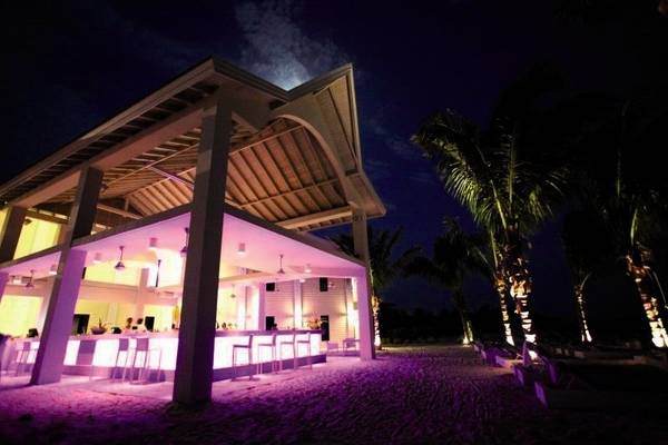 Nachtansicht des Papagayo Beach Hotel & Resort Curacao mit beleuchteter Bar und Loungebereich am Strand.