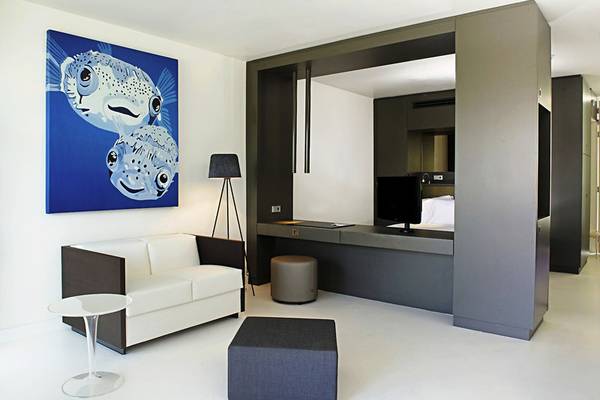 Innenansicht der Suite im Papagayo Beach Hotel & Resort Curaçao mit weißem Sofa, Schreibtisch und Fernseher.