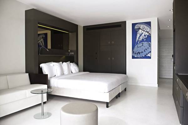 Modernes Zimmer im Papagayo Beach Hotel & Resort Curaçao mit weißem Bett, grauen Möbeln und blauem Wandbild.