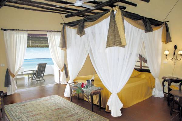 Schlafzimmer im Karafuu Beach Resort & Spa mit Bett, Vorhängen und Meerblick.