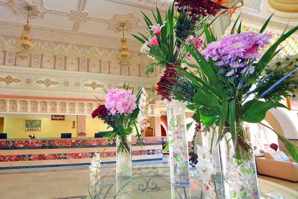 Lobby des Pickalbatros Alf Leila Wa Leila Resorts mit großen Blumenvasen und Rezeptionstresen.